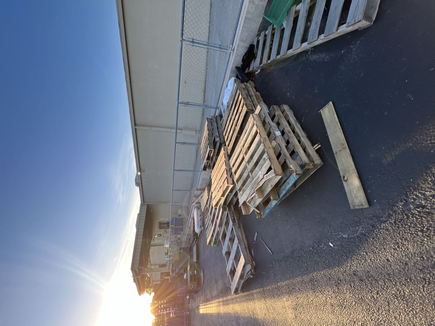 Stacks of free reclaimed pallets in a parking lot at sunset