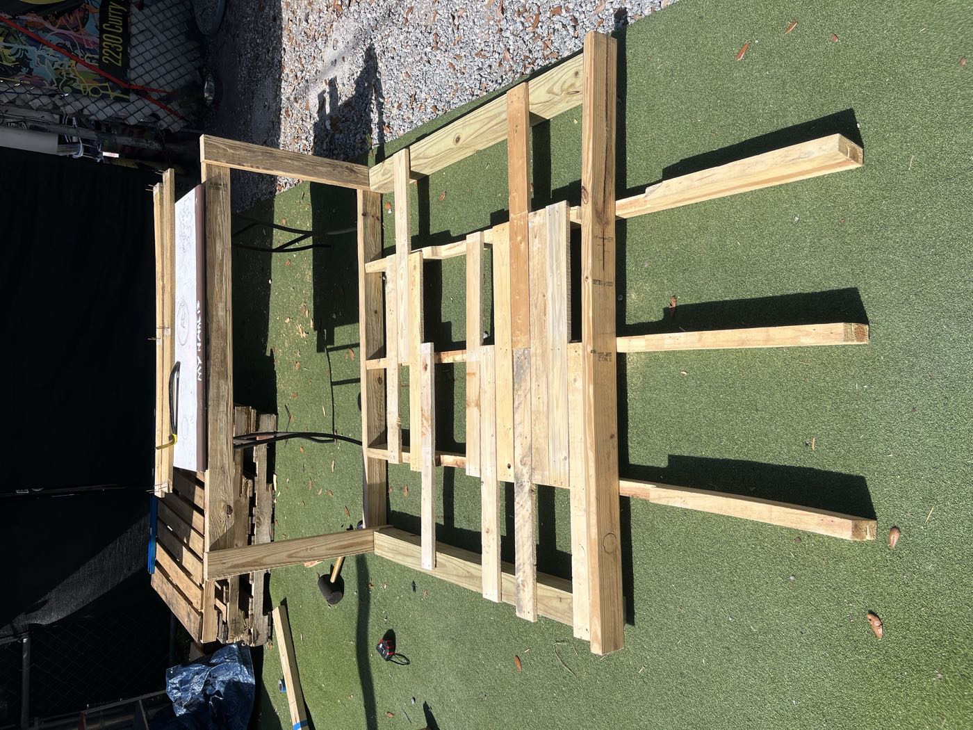 Pallet boards and frame parts laid out flat on artificial turf